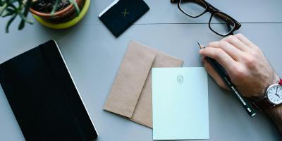Overhead view of a desk with writing tools, glasses, envelope, and notebooks, showcasing office work essentials.