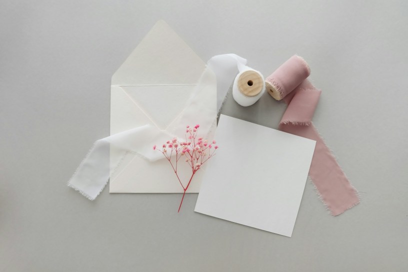 a white envelope with a pink flower and a pair of scissors next to it